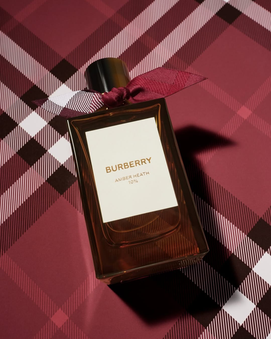 Burberry fragrance product photo: clear glass, amber brown, white label and black cap, glass, studio light, image 2 of 2