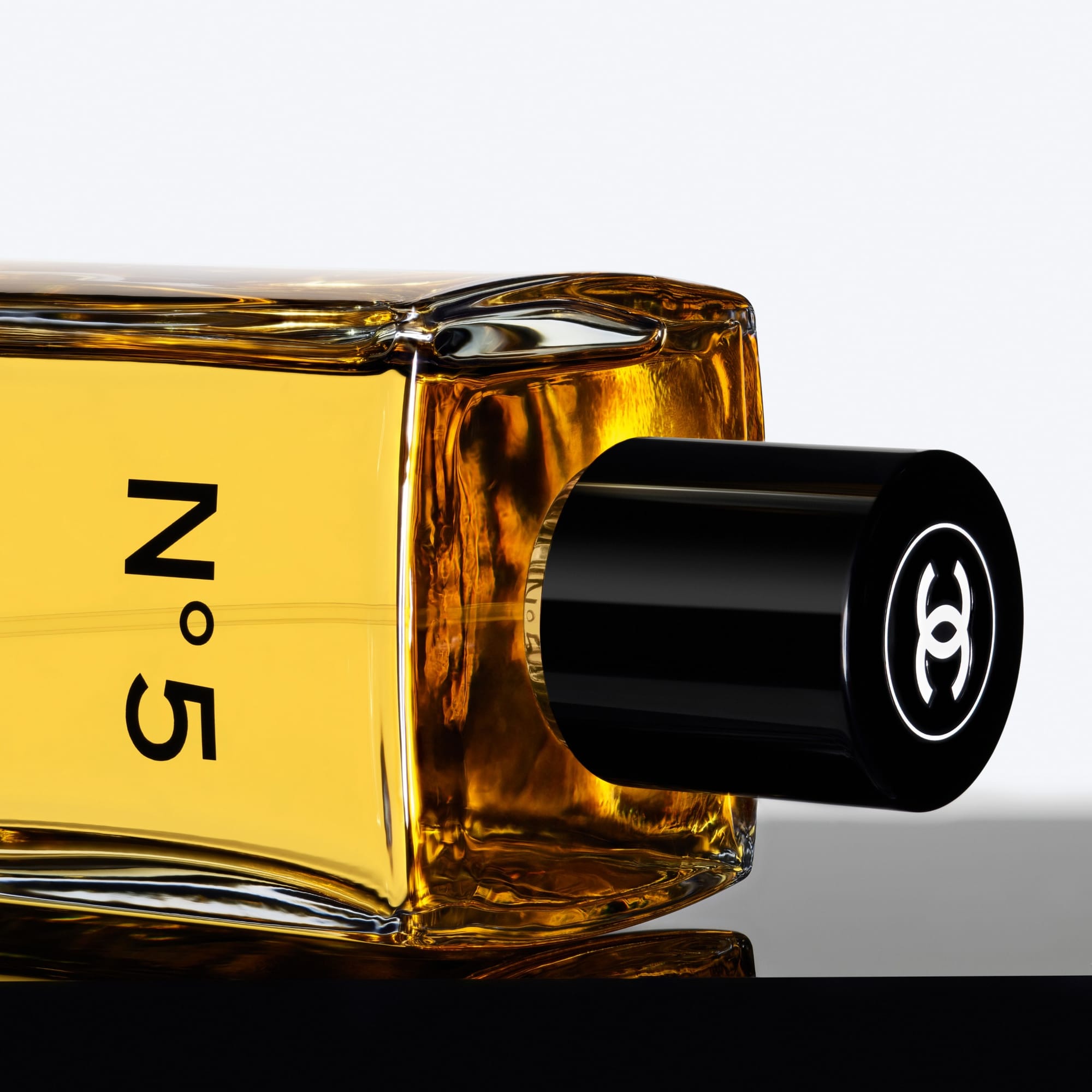 Chanel N°5 product photo: golden yellow, black cap and amber, glass, studio light