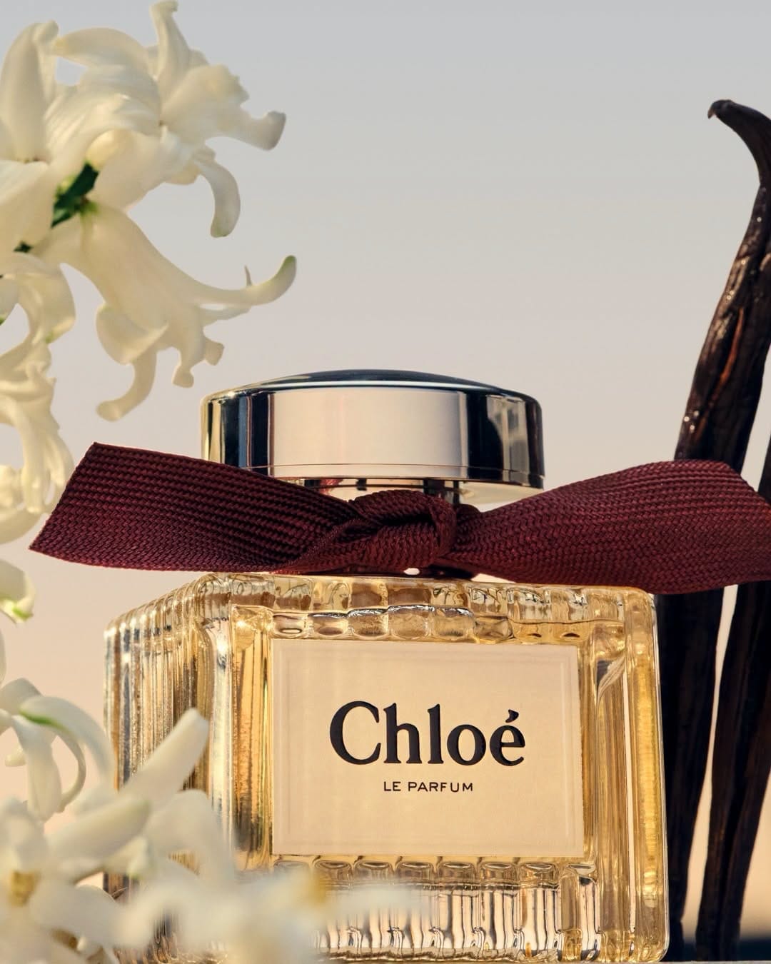Chloé perfume product photo: amber gold, burgundy and brushed silver, glass, natural light
