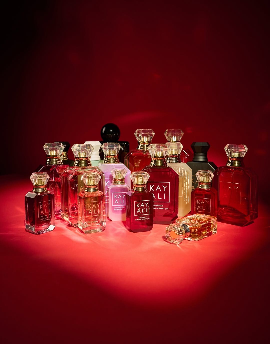 Kayali fragrance product photo: ruby red, peach and rose pink, glass, dramatic light, image 3 of 4