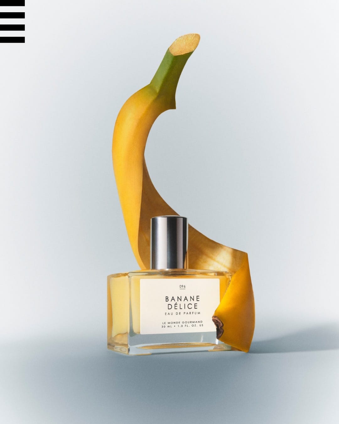 Le Monde Gourmand's Banane Délice product photo: banana yellow, clear glass, silver cap and white label, glass and organic, soft light