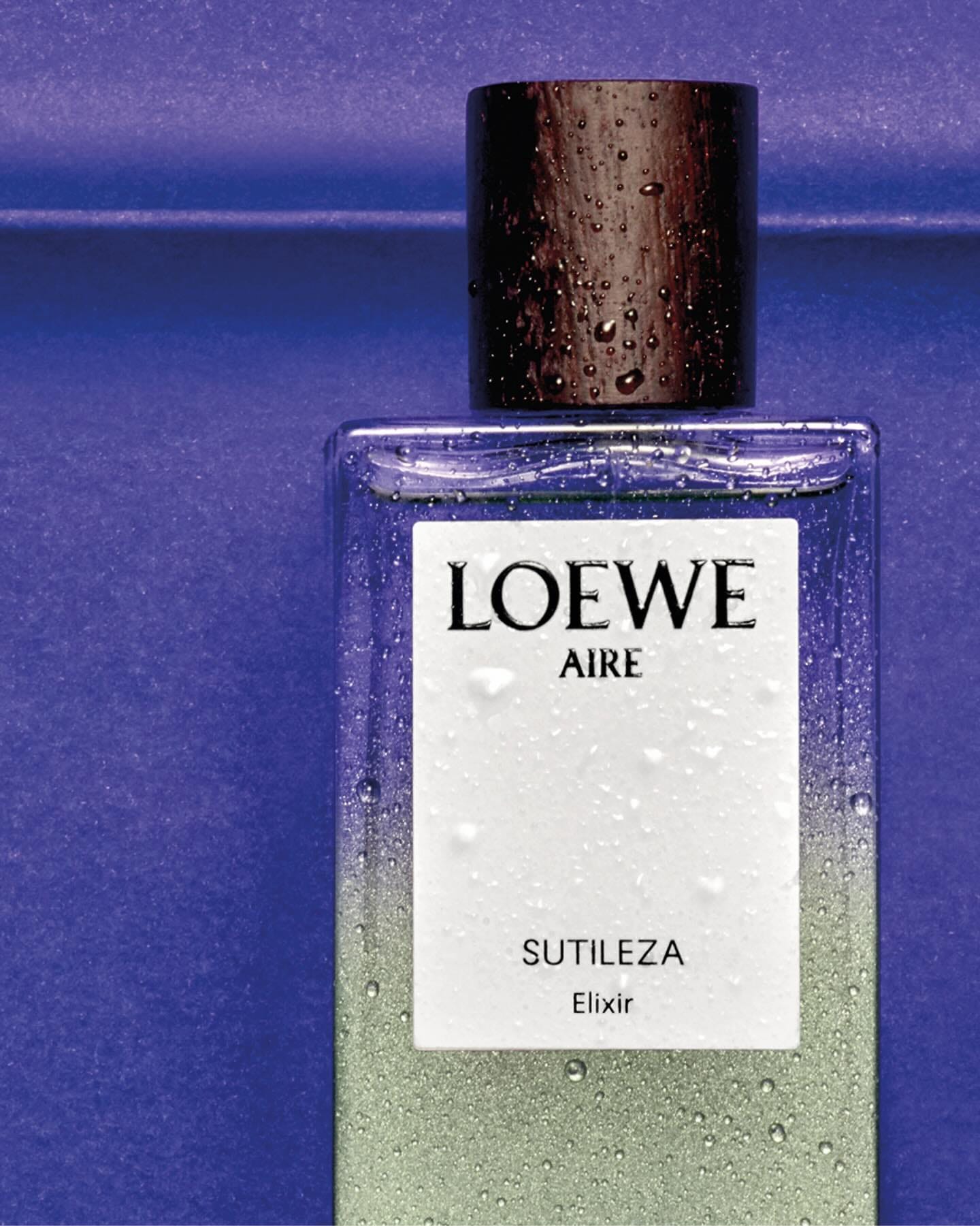 Loewe Aire Sutileza Elixir product photo: clear glass, sage green, white label and black cap, glass, studio light