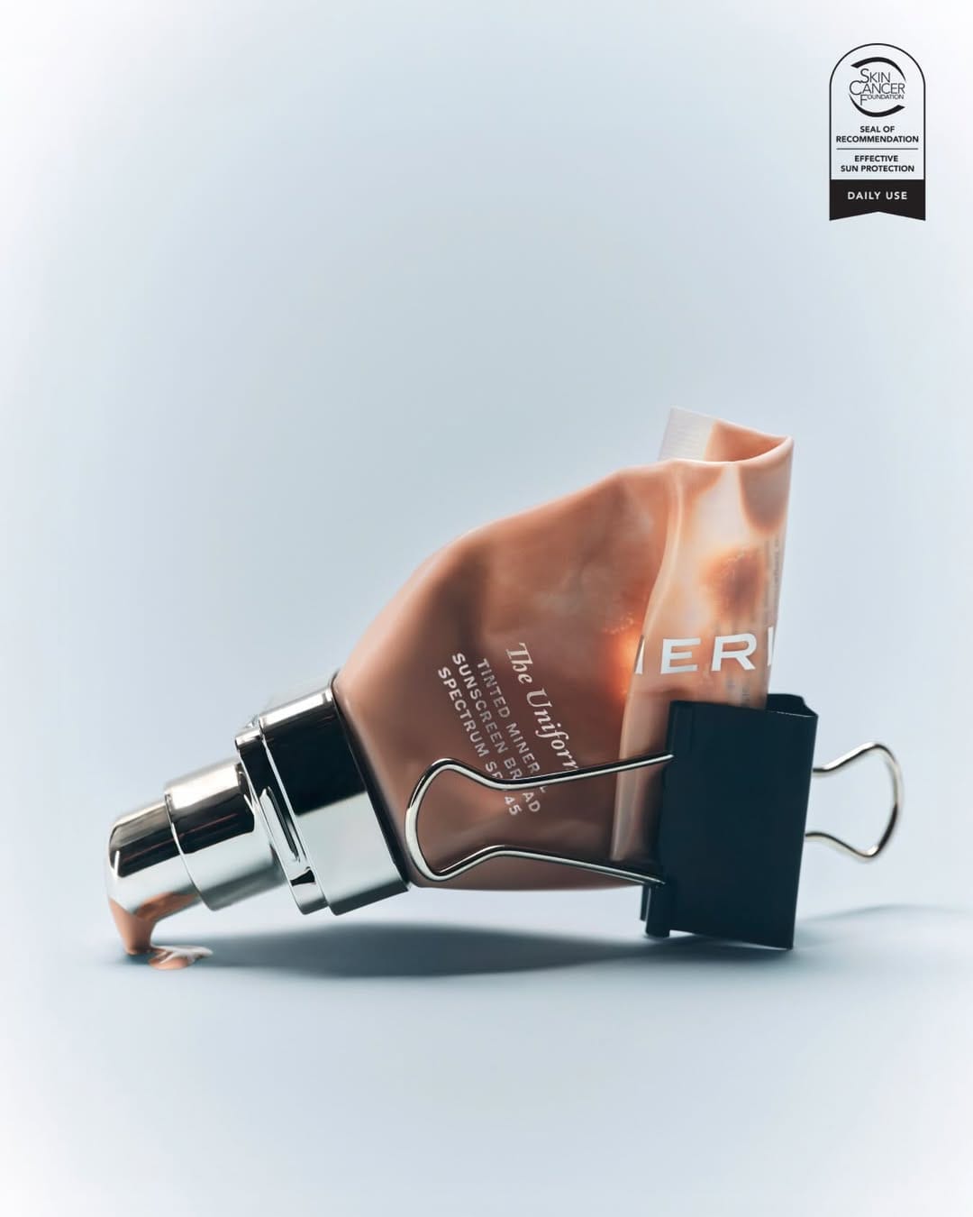 MERIT sunscreen product photo: peach, dusty rose and brushed silver, plastic, natural light