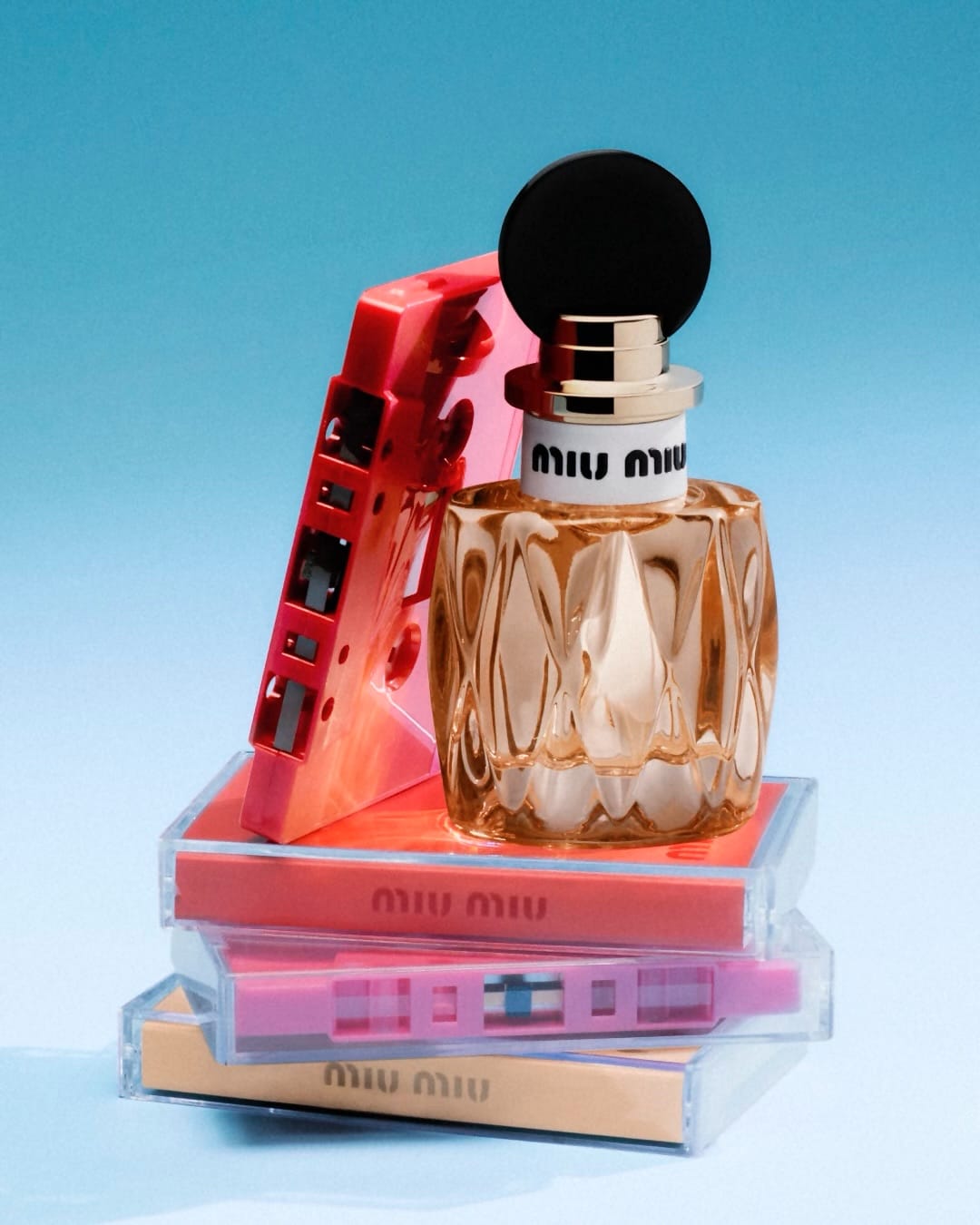 Miu Miu fragrance product photo: aqua blue, peach amber, black cap and gold, glass, soft light, image 2 of 3