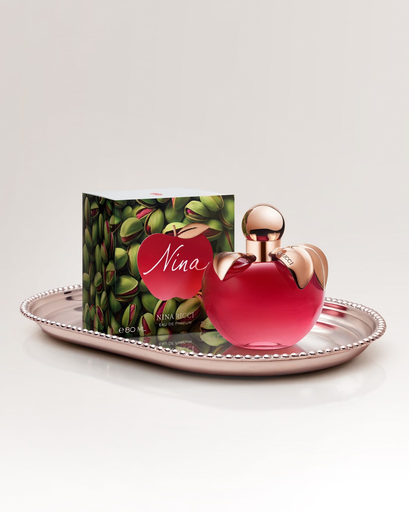 Nina Ricci's anniversary parfum product photo: ruby red, rose gold and blush pink, metal, soft light