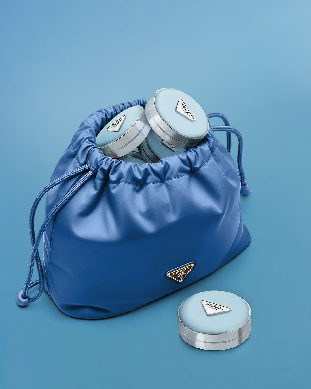 Prada Beauty product photo: periwinkle blue and brushed silver, fabric, soft light, image 1 of 2
