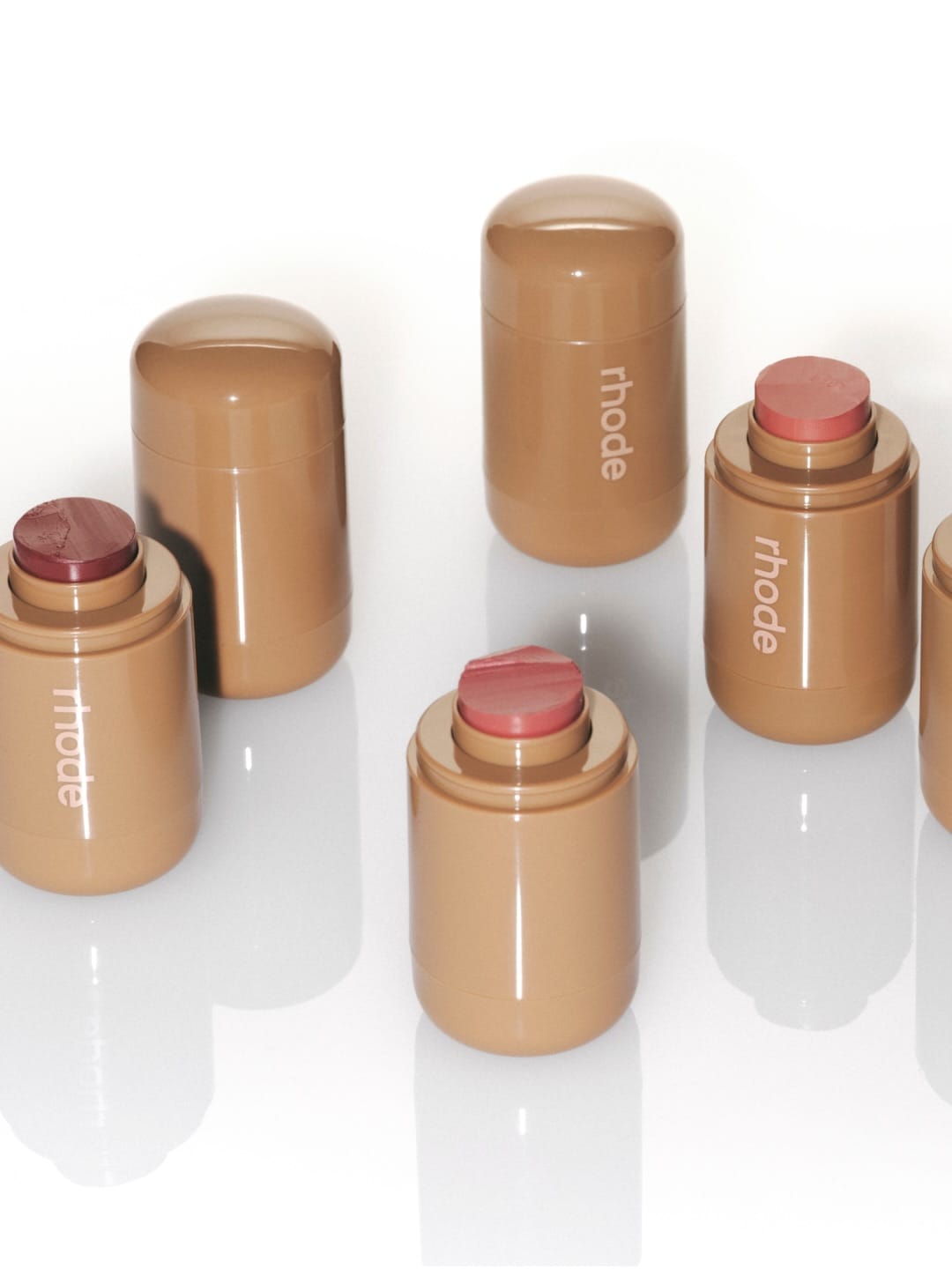 Rhode Skin blush sticks product photo: caramel tan, sand beige and berry pink, plastic, soft light