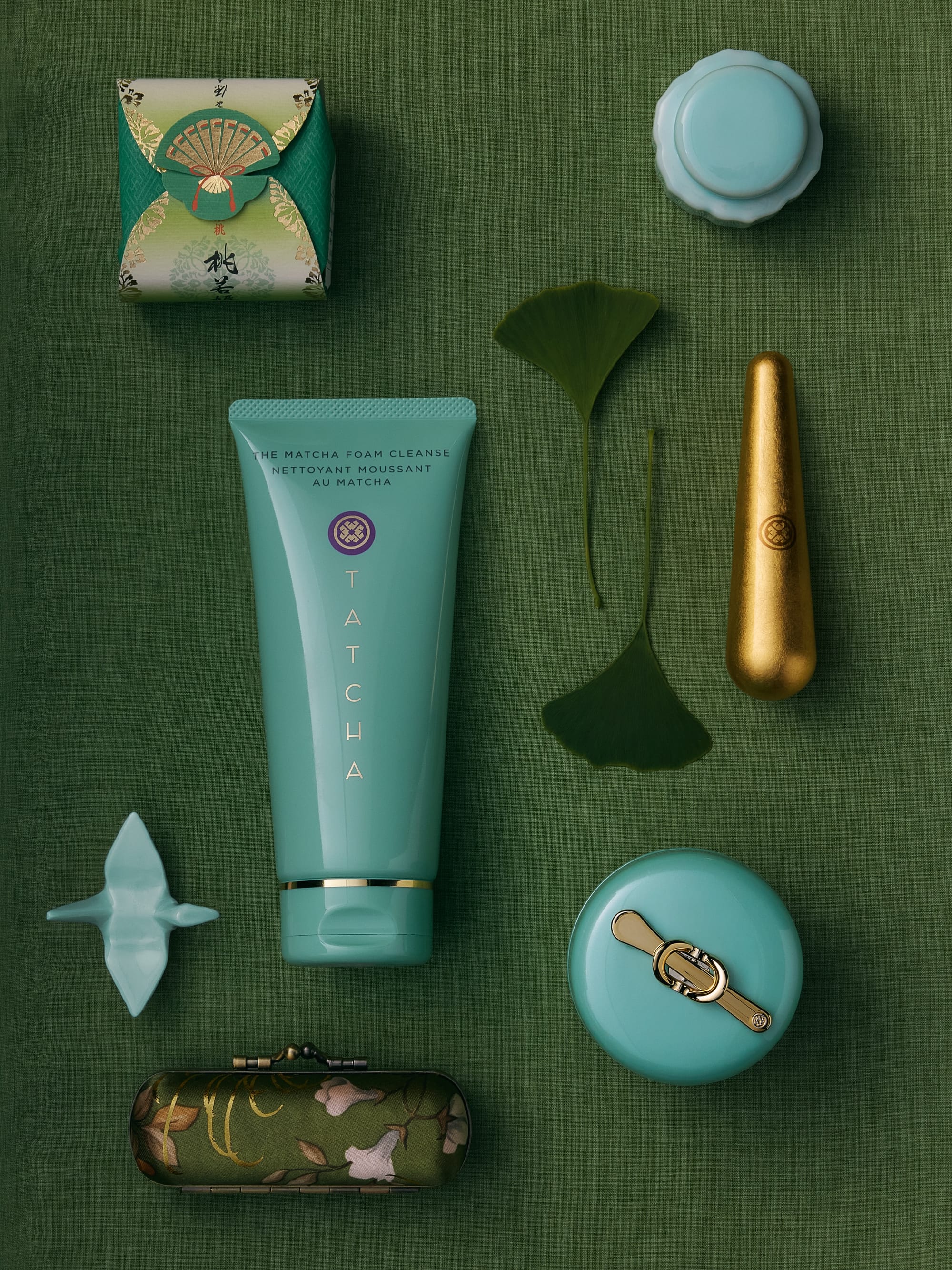 Tatcha skincare product photo: jade teal, periwinkle purple and brass gold, fabric, soft light